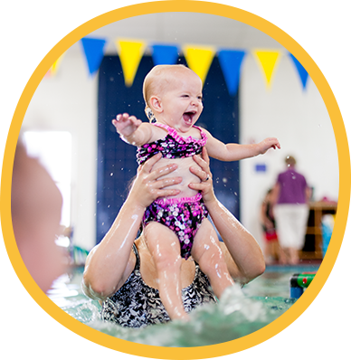 Baby laughing and kicking in the pool as a parent lifts them up